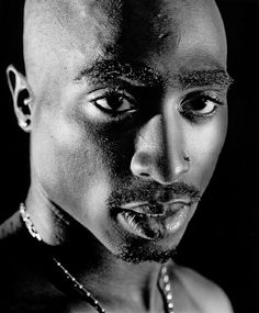 a black and white photo of a man with piercings on his face, looking at the camera