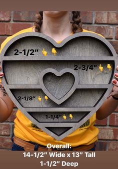 a woman holding up a heart shaped cutout with measurements for the size and width