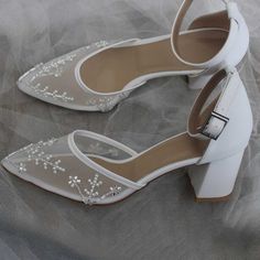 Elevate your bridal look with these exquisite white tulle ankle strap bridal heels adorned with shimmering pearls and beads. Perfect for a touch of elegance on your special day. Color: White Material: Tulle Heel Type: Block heel Heel Height: 3.15'' / 80 mm approx Product measurements were taken using size 8. Please note that measurements may vary by size. Toe: Pointy toe Pearl and bead embellished design Adjustable buckled ankle strap design Handcrafted US sizing. Fits true to size. Embellished Ankle Strap Wedding Shoes, White Embellished Heels For Prom, White Embellished Ankle Strap Heels, Elegant Tulle Heels For Wedding, Elegant Tulle Wedding Heels, White Ankle Strap Wedding Shoes For Bridal Shower, White Pearl Embellished Pointed Toe Wedding Shoes, Party White Heels With Pearl Embroidery, White Tulle Bridal Accessories For Evening