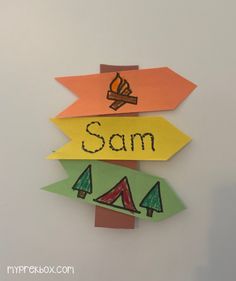 the name sam is written on colorful paper cut out to look like trees and campfires