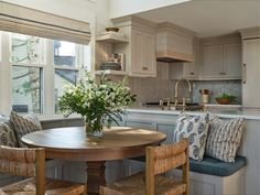 a kitchen table with two chairs and a vase filled with flowers on top of it