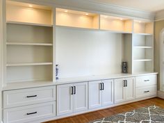 an empty room with white cabinets and drawers on the wall, along with a rug