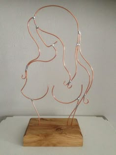 a sculpture made out of copper wires on a wooden stand