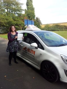 a woman standing next to a white car holding a piece of paper in her hand