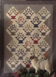 a sheep is standing in front of a quilt