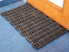 a door mat on the floor in front of a wooden door with blue tile floors