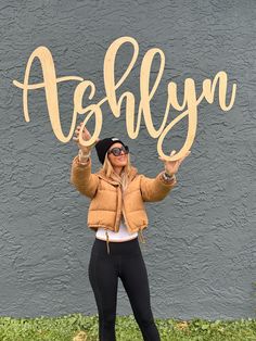 a woman standing in front of a gray wall holding up a wooden sign that says,'absolutely '