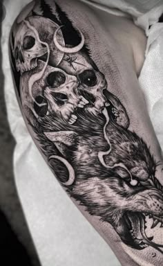 a man's thigh with skulls and wolfs on it