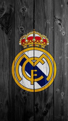 the real madrid crest on a wooden wall with wood planks in the foreground