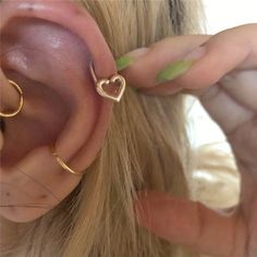 a close up of a person wearing gold ear rings and an ear cuff with a heart on it