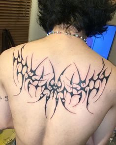 the back of a woman's upper body with an intricate tattoo design on it