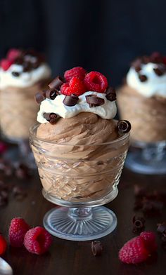 three desserts in small glass dishes with raspberries on top