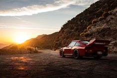 a red sports car parked on the side of a mountain road at sunset or sunrise