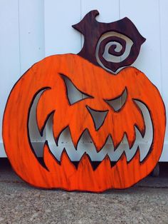 an orange carved pumpkin sitting in front of a white door with a spiral design on it