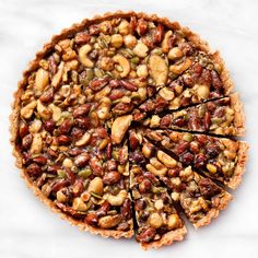 a pie with nuts and other toppings cut into slices on a white table top