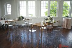 several clear chairs and tables in a room with windows on either side of the table