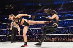 two women are wrestling in a ring with an audience watching them from the sidelines