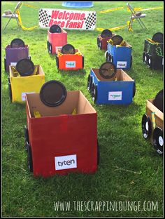 several small toy cars sitting on top of a green grass covered field next to a welcome sign