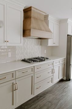 a stove top oven sitting inside of a kitchen next to white cupboards and drawers