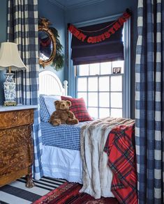 a teddy bear sitting on top of a bed in a room with blue walls and curtains