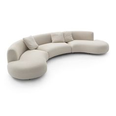 a curved couch with pillows on it in front of a white background and back ground