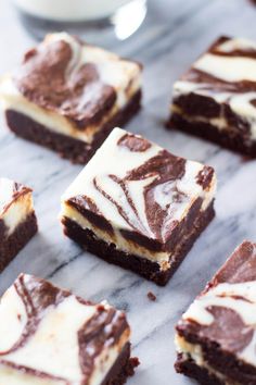 several pieces of brownie with white frosting and chocolate swirls on top, sitting on a marble surface