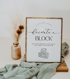 a white sign sitting on top of a wooden table next to a vase filled with dry grass