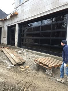 a man standing in front of a building under construction next to a wooden bench and garage door