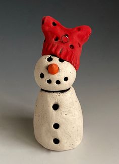 a ceramic snowman with a red hat on its head