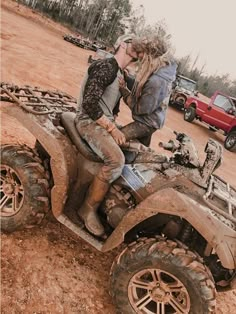 two people kissing while riding an atv in the mud