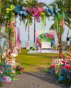 an outdoor wedding ceremony with flamingos and flowers on the grass, surrounded by palm trees