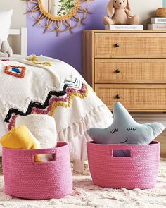 two pink baskets with stuffed animals in them sitting on a rug next to a bed