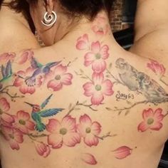 the back of a woman's shoulder with flowers and birds painted on her chest