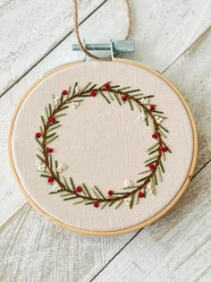 an embroidered wreath with red berries and greenery