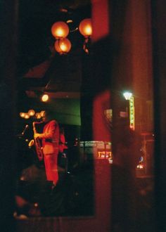 a man is playing the saxophone in a dimly lit room with lights hanging from the ceiling