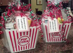 two popcorn bags wrapped in red and white paper with candy canes tied around them