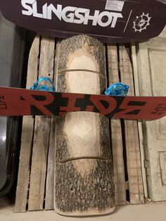 a snowboard is propped up against a wooden structure with the word slingshot written on it