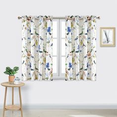 the window curtain is decorated with flowers and birds on white fabric, along with a small side table in front of it