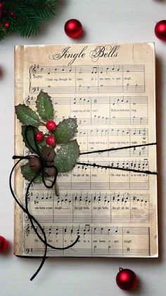 an old sheet with holly and berries on it, surrounded by christmas decorations in red balls