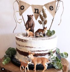 there is a cake decorated with animals and bunting banner on it's side