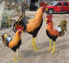 three roosters are standing in the dirt