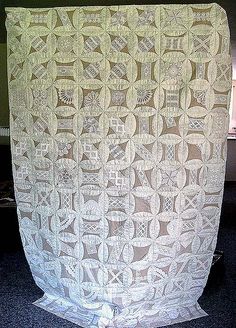 a white crocheted blanket hanging from a wall