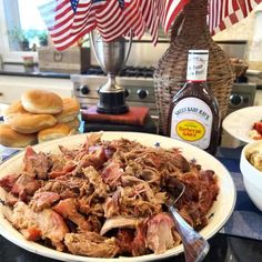 pulled pork is served on a plate with bread rolls and an american flag in the background