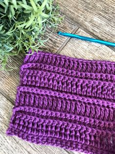 the crochet is laying on the wooden floor next to a plant and knitting needles