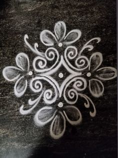 a drawing of a flower with swirls and dots in the center on a black surface