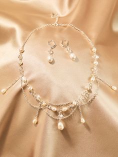 a necklace and earring set with pearls on a gold satin background, close - up