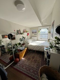 a bedroom with a bed, plants and pictures on the wall in it's corner