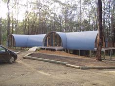 a car is parked in front of a house that has been built into the woods