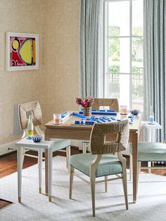 a dining room table and chairs in front of a window with blue drapes on the windowsill