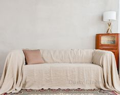 a living room with a couch covered in a blanket and a lamp next to it